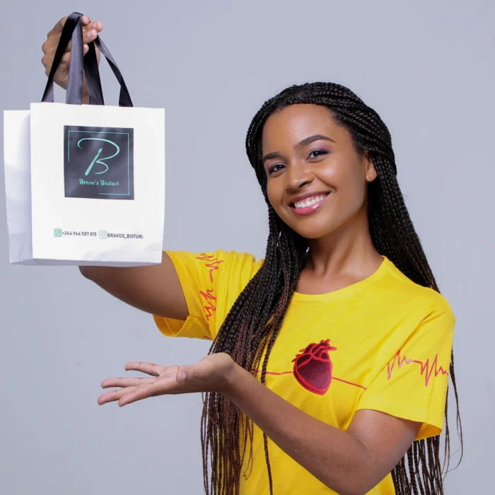 Modelo usando camiseta amarela Feel the Beat e segurando sacola da Bravo's Bisturi